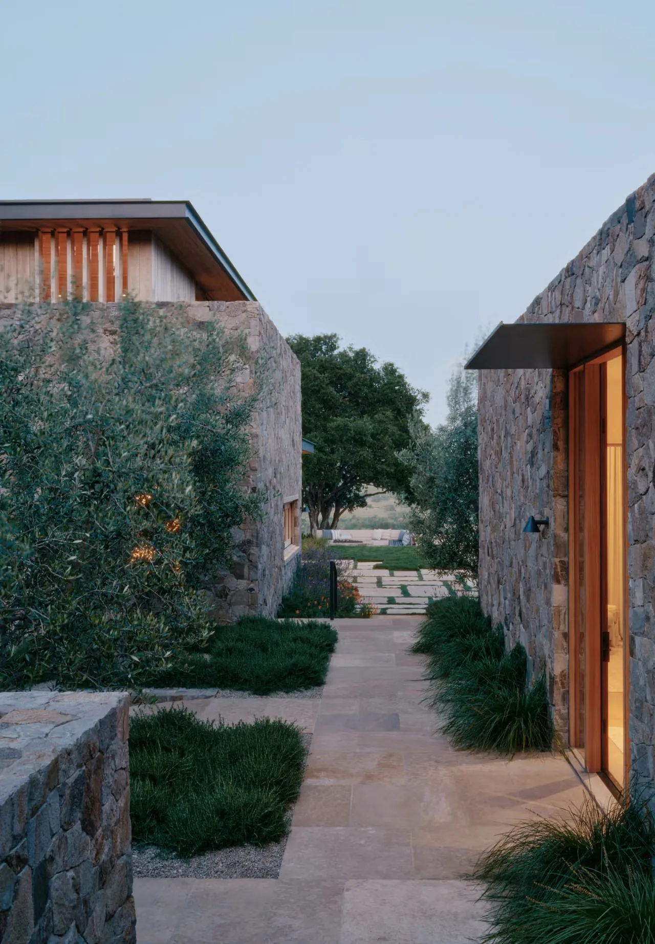 Corridor between two stone buildings at the Stone Villa, showcasing stone walls, paved path, and landscape greenery.