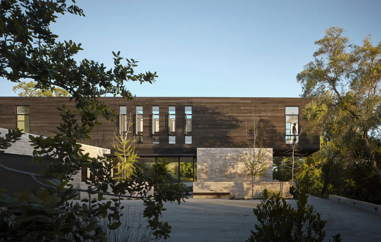 The Guzhai project features a modern exterior with wood siding and textured stone walls, blending with surrounding trees.