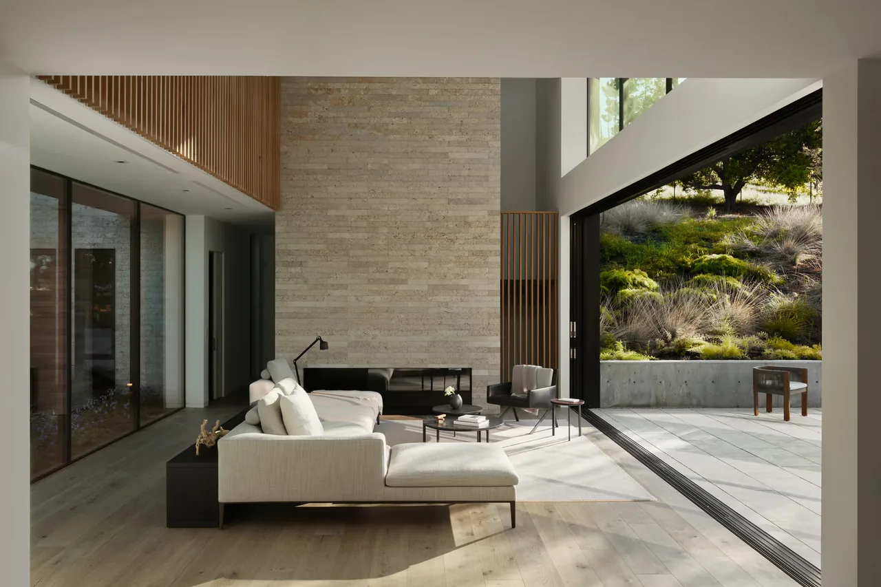 Open living room with floor-to-ceiling stone fireplace and sliding glass doors to a landscaped patio.