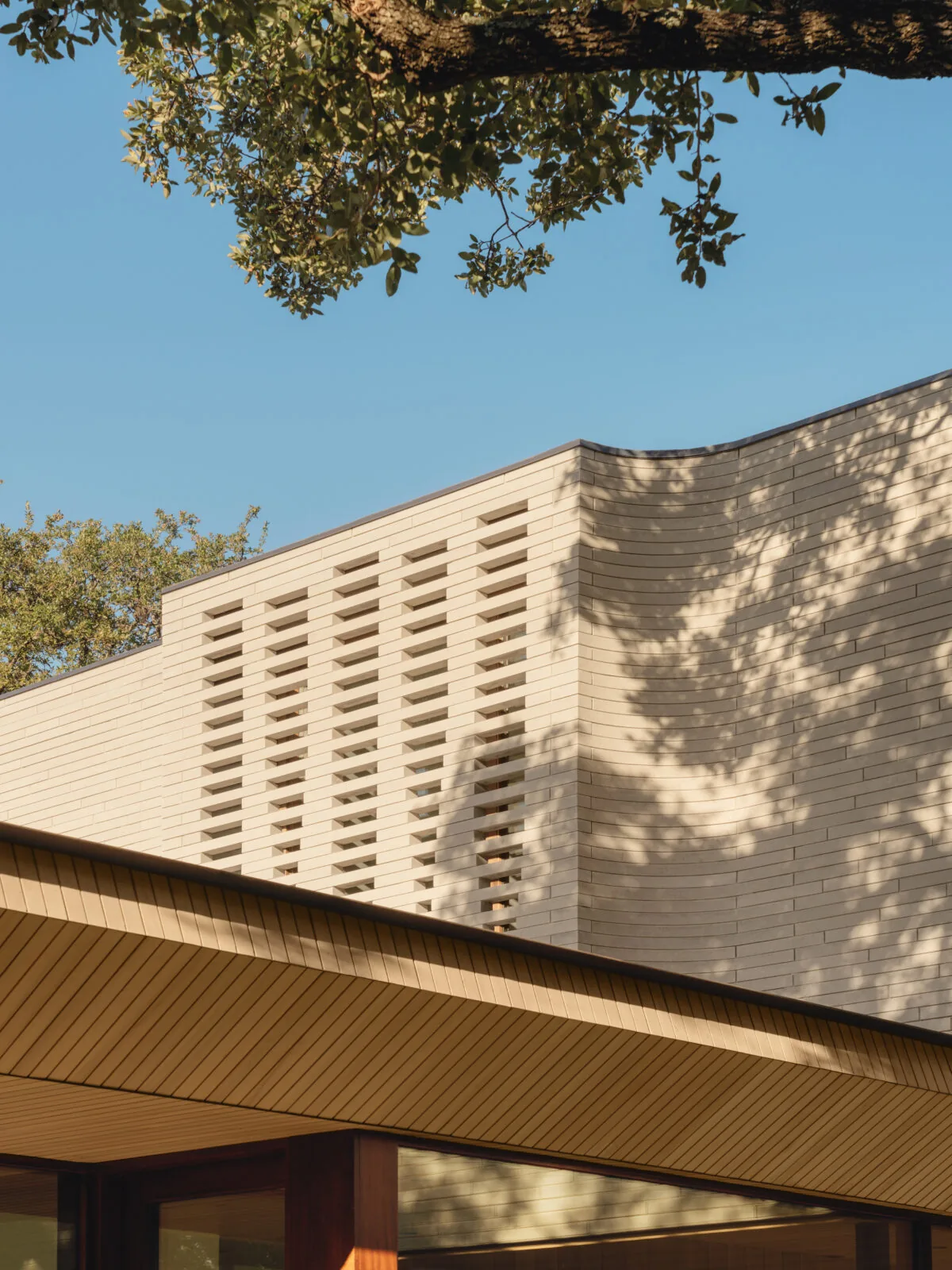 The Greenbelt Residence features horizontal light brick cladding with a perforated section for ventilation or light.