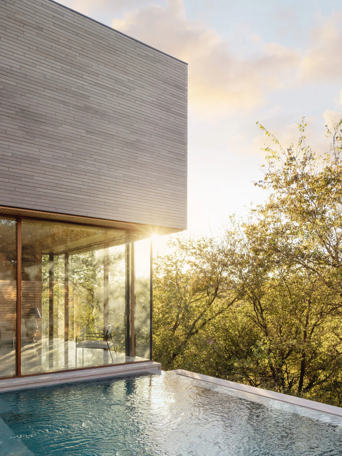 Greenbelt Residence features floor-to-ceiling glazing and a reflecting pool adjacent to a modern minimalist exterior.
