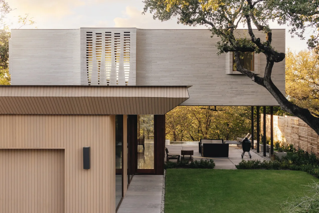 Greenbelt Residence features a cantilevered design with a covered patio and outdoor seating area blending with the wooded landscape.