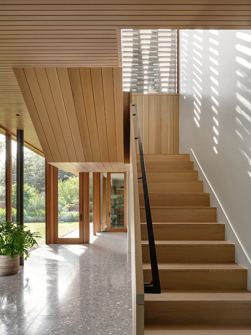 Hallway featuring a wooden staircase and terrazzo flooring with large glass doors opening to the outside.