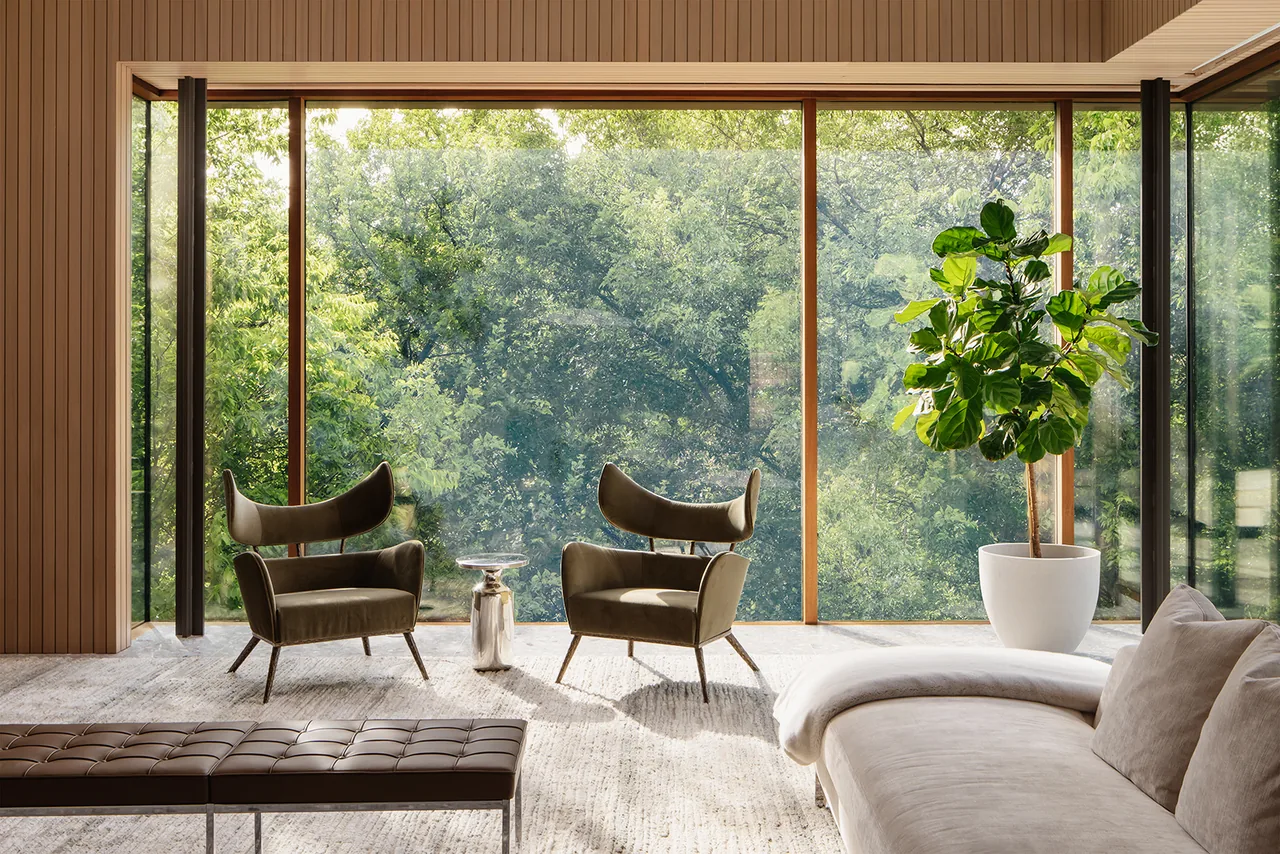 Living room in Greenbelt Residence features floor-to-ceiling windows overlooking greenery and modern furniture.