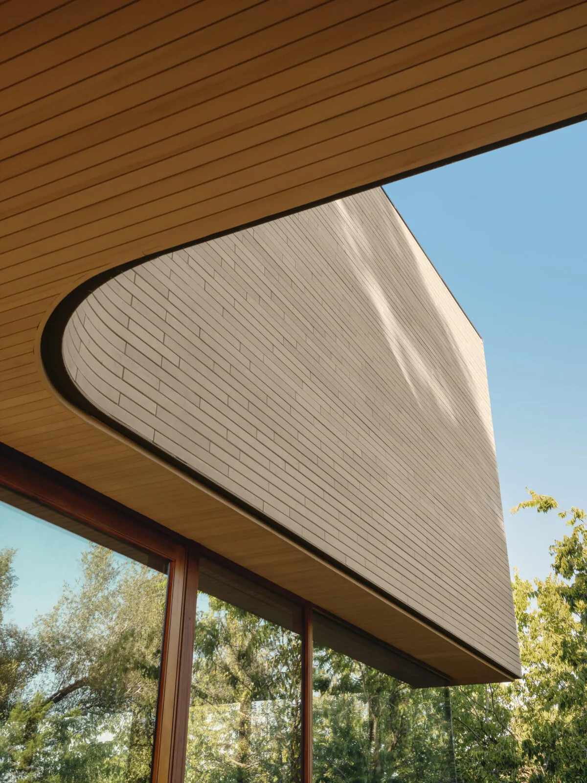 Modern home exterior with wood slat soffit and white brick wall at Greenbelt Residence.