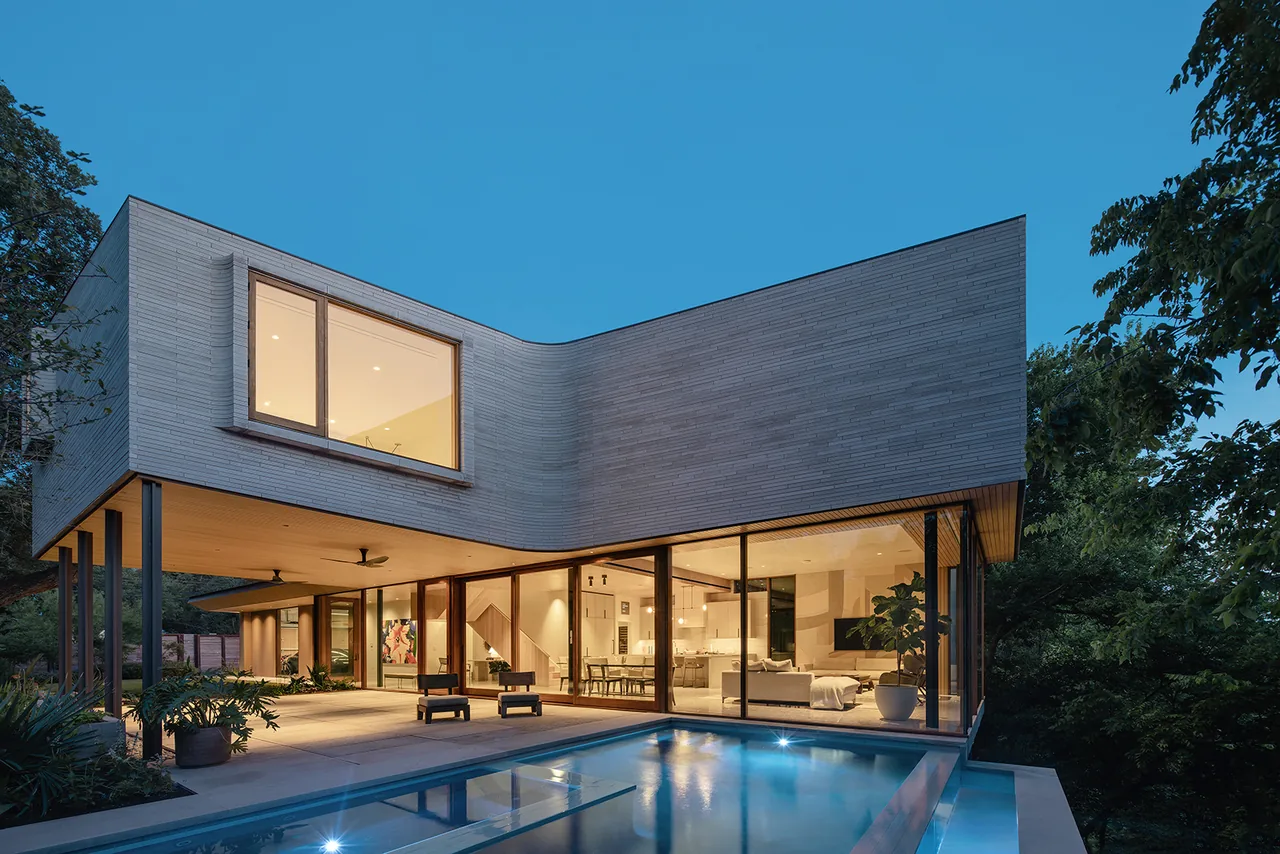 Greenbelt Residence features a curved white brick exterior with wood soffits, expansive glass walls, and an outdoor pool.