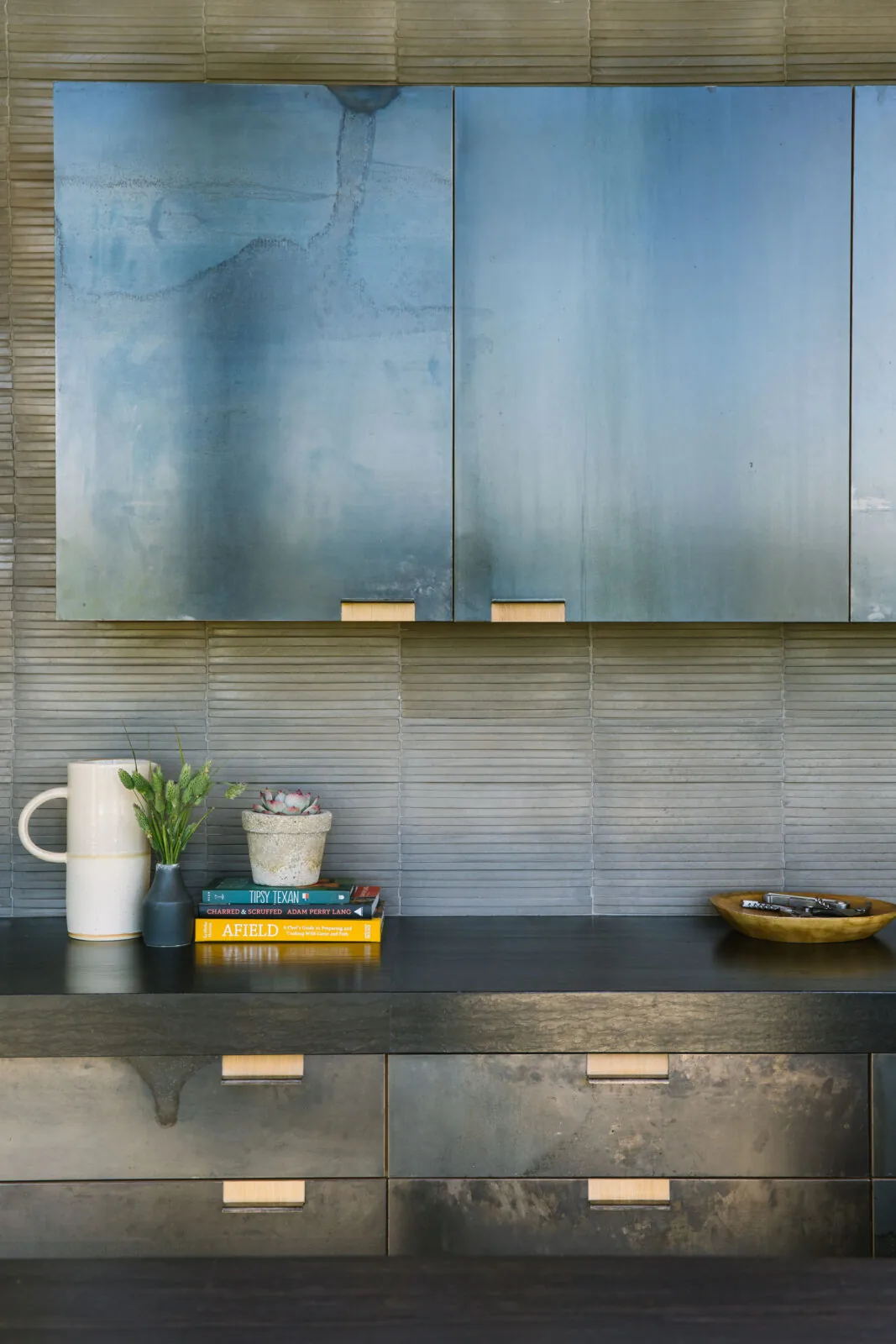 Metallic blue kitchen cabinets with black countertop in a modern setting.