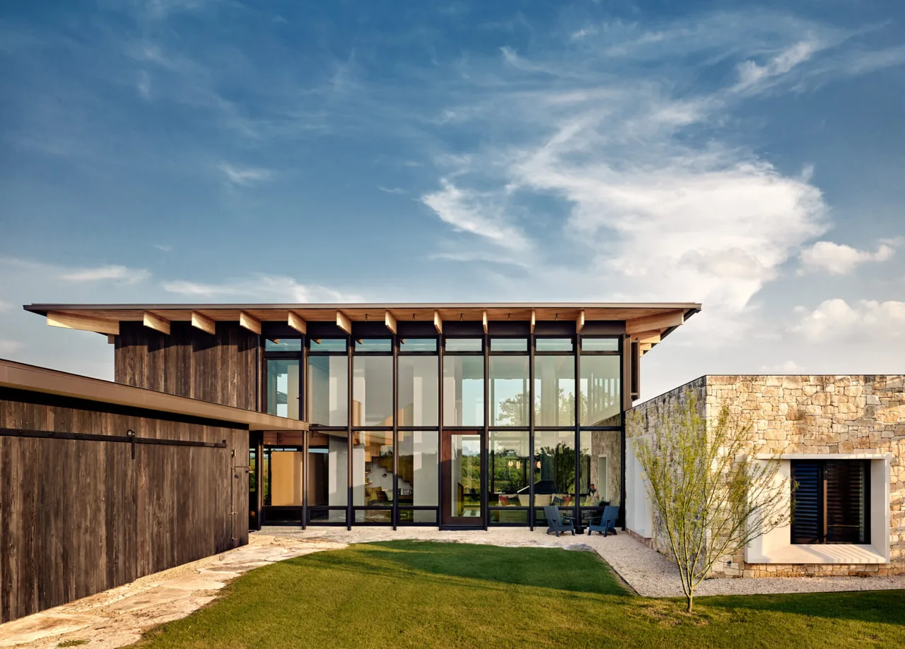 The Llano Retreat features large floor-to-ceiling glazing with dark wood siding and stone walls.