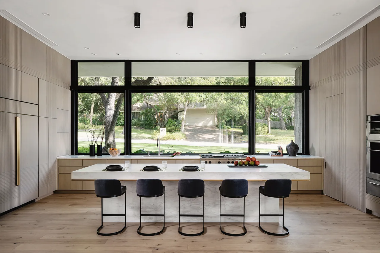 Rollingwood Residence kitchen with large island seating and floor-to-ceiling black-framed windows by Hsu Office of Architecture.