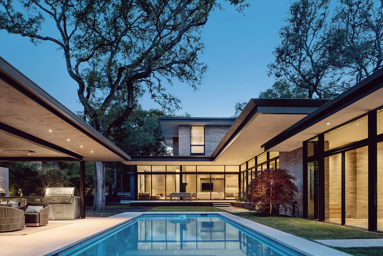 The Rollingwood Residence by Hsu Office of Architecture shows a modern home with expansive glass walls and a pool area at dusk.