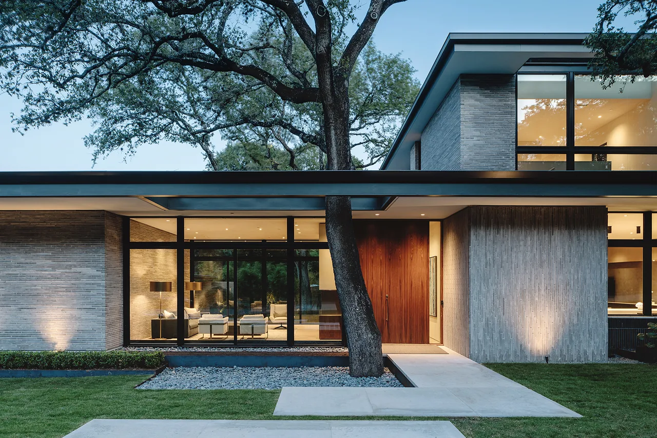 Rollingwood Residence features floor-to-ceiling glazing, a flat roof, and wood siding by Hsu Office of Architecture in Austin.