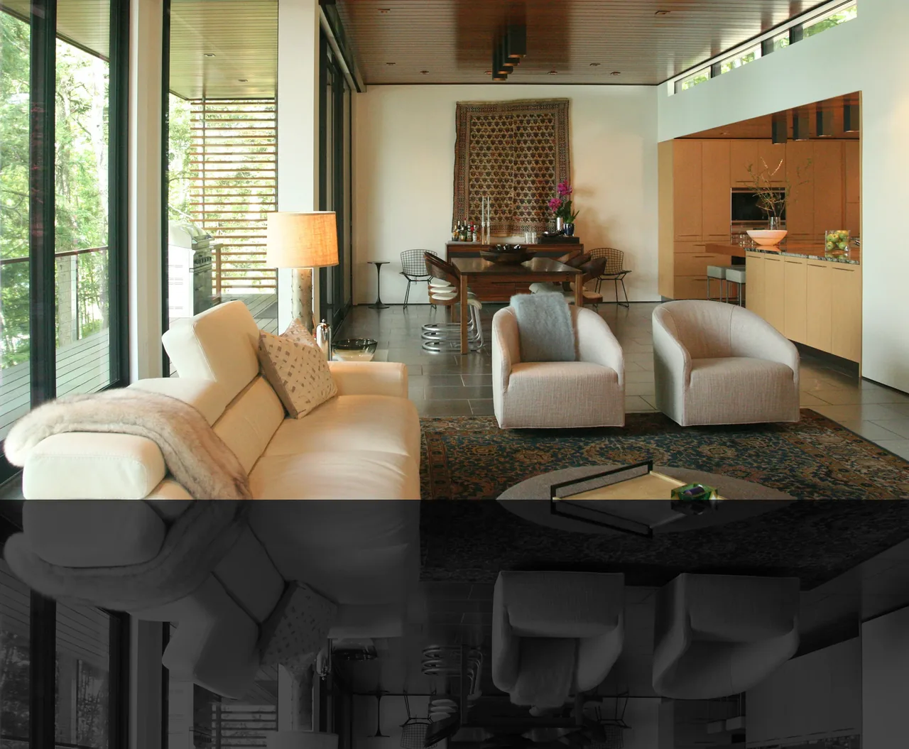 The Walloon Lake House features an open living room and kitchen with large glazing and wood finishes.