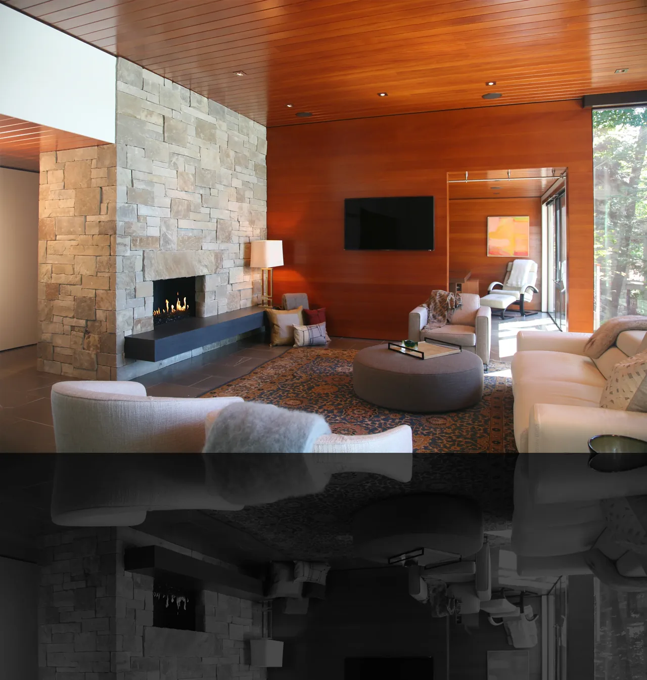 Living room features a stone fireplace, wood panel ceilings and walls, and a television mounted above a seating area with a large rug.