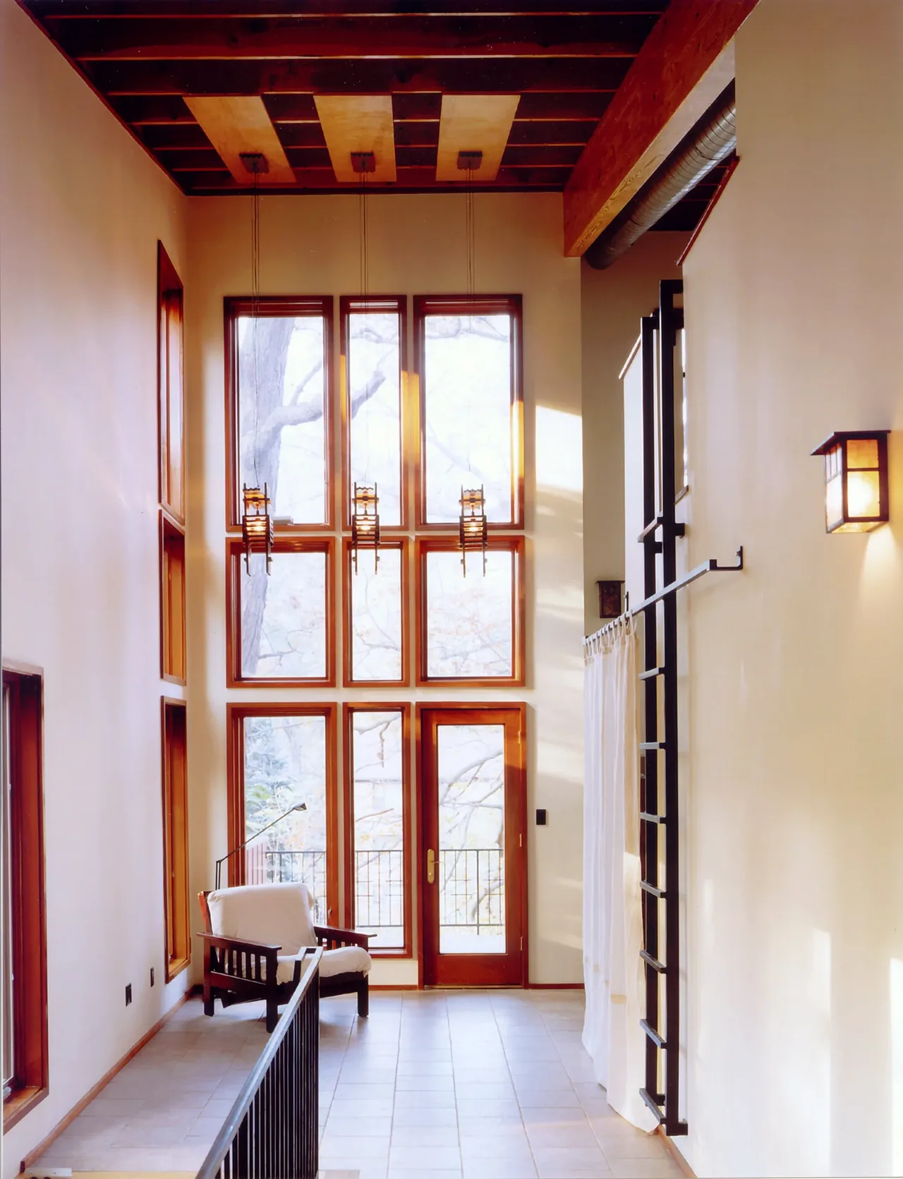Perch House interior features tall vertical windows, a wood-beamed ceiling, and a tile floor entry with a wooden framed door.