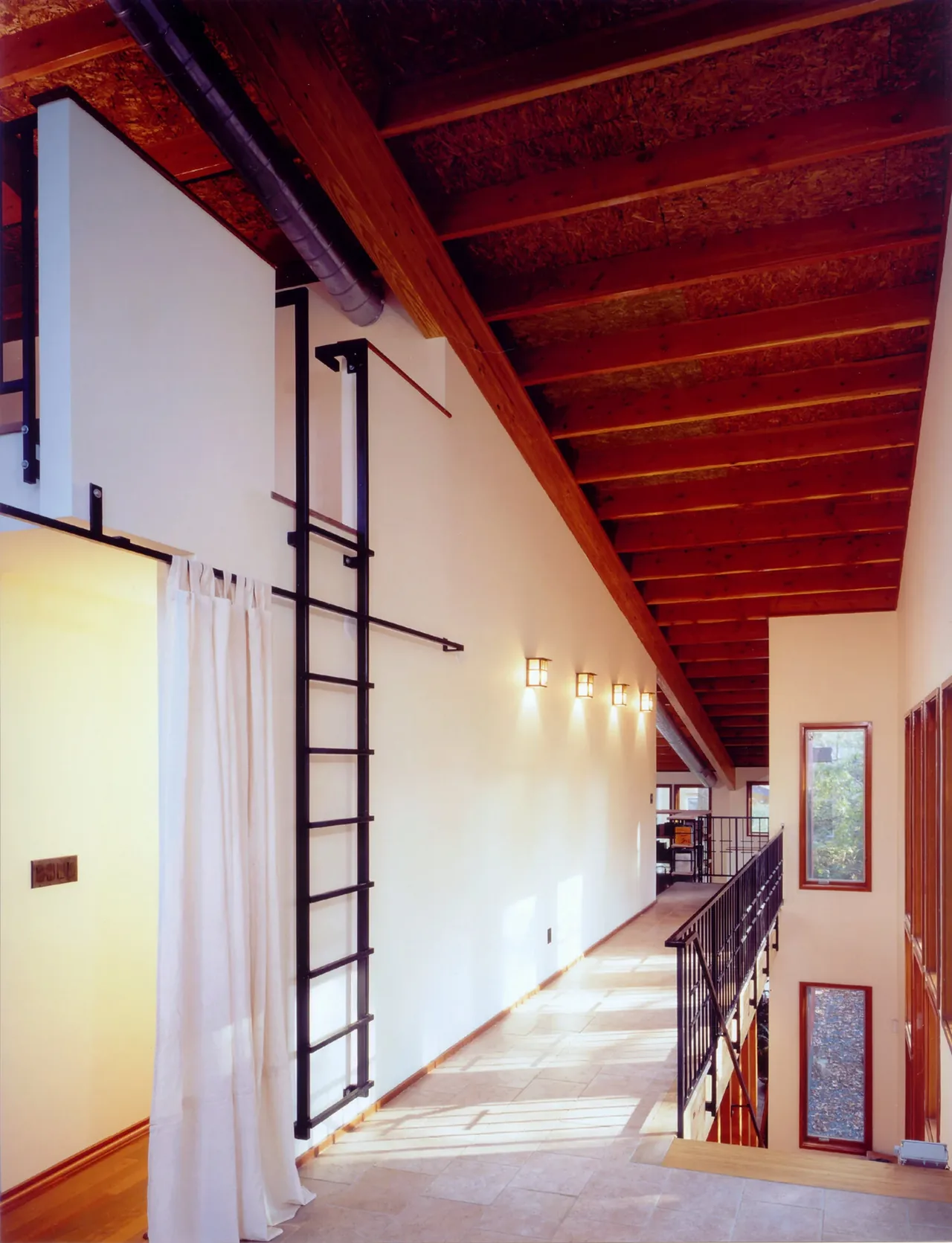 Long hallway with wooden ceiling beams and narrow vertical windows at the Perch House.