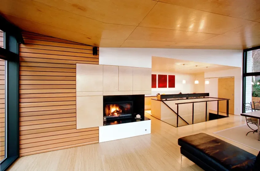 Modern living room with horizontal wood siding and a built-in fireplace near the kitchen area.