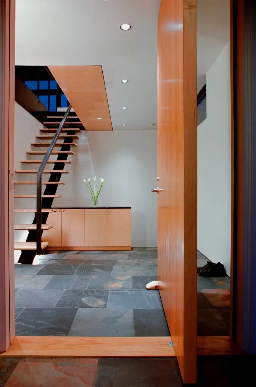 Entryway with floating stairs and built-in cabinetry in a modern style home.