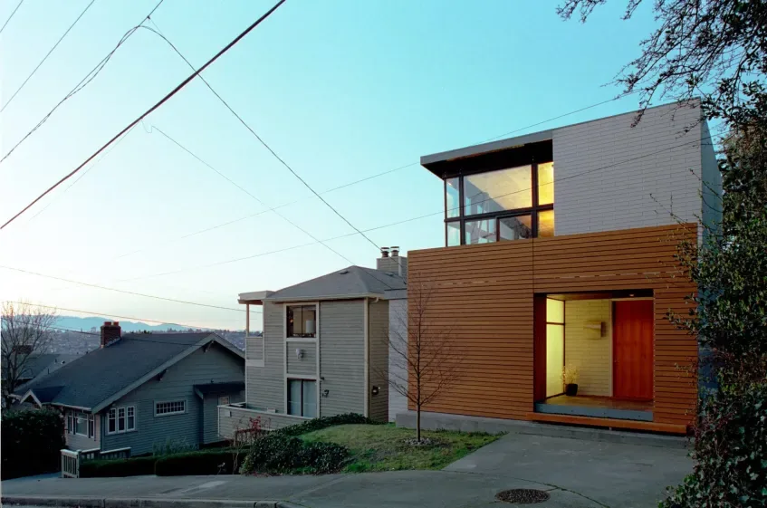 Cavehill project features a two-story modern home with horizontal wood panels and large black window frames above the entry.
