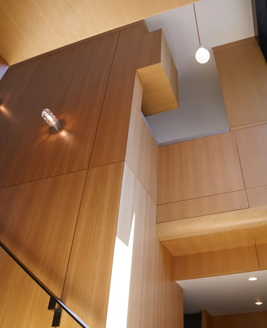 Interior shot showing extensive wood paneling with a round hanging pendant light and a metal industrial-style wall sconce.