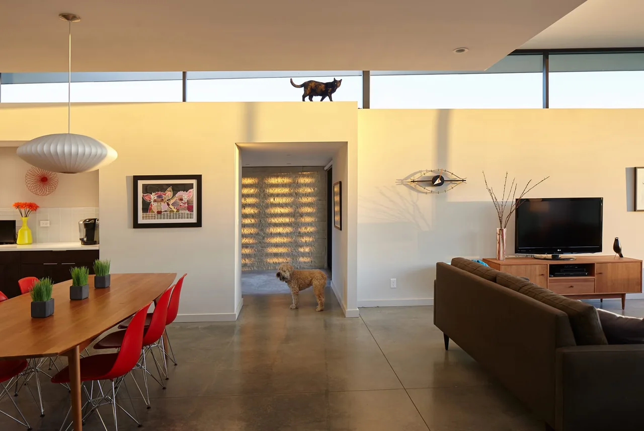 Modern open living and dining area with concrete floors and natural light from clerestory windows at Byers Residence.