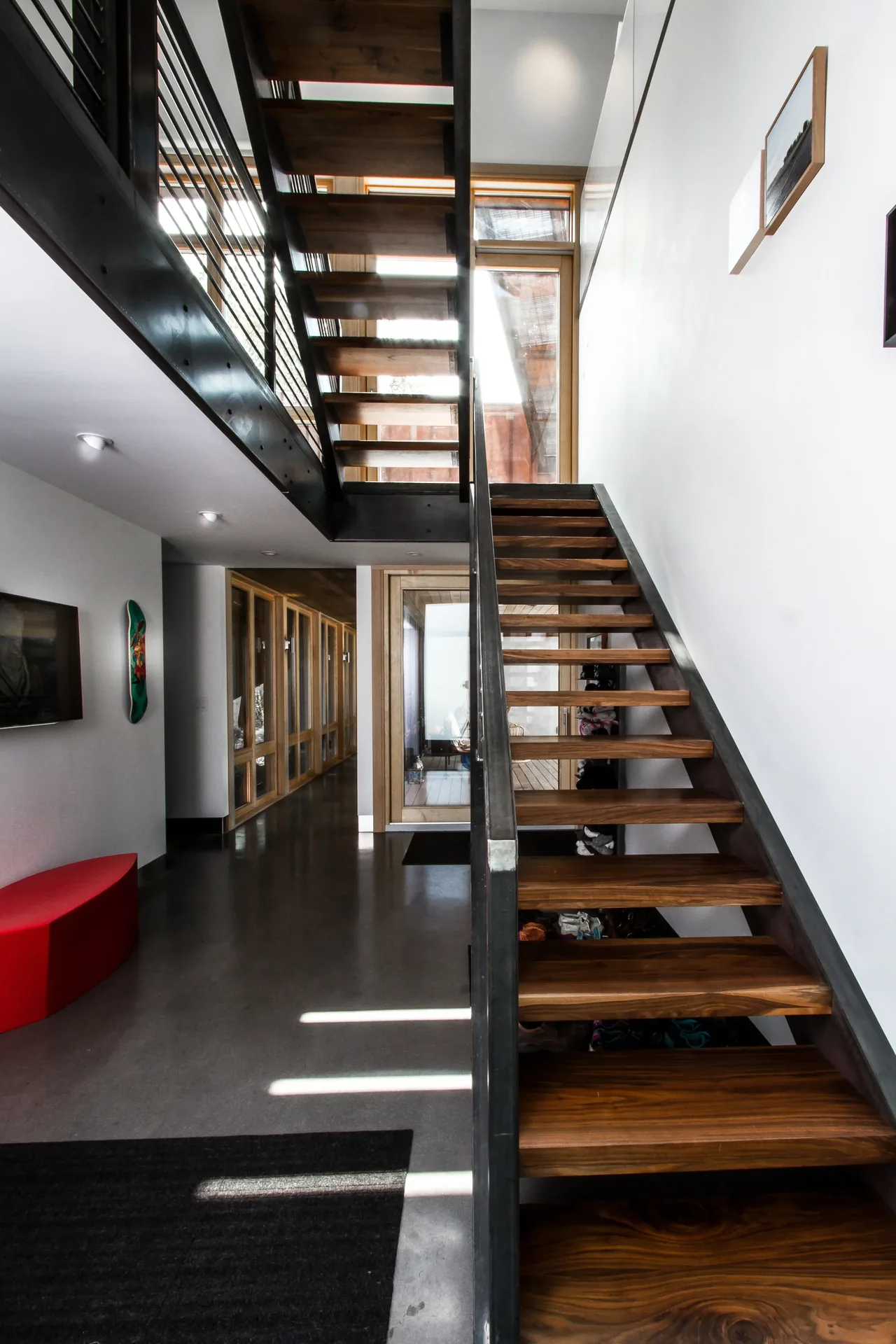 The stair connects two levels inside the Wren Residence, showcasing wood and metal materials.