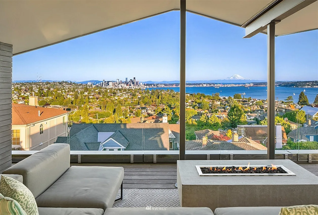 Outdoor living space featuring modern seating and a built-in fire pit with panoramic city and mountain views in Seattle.