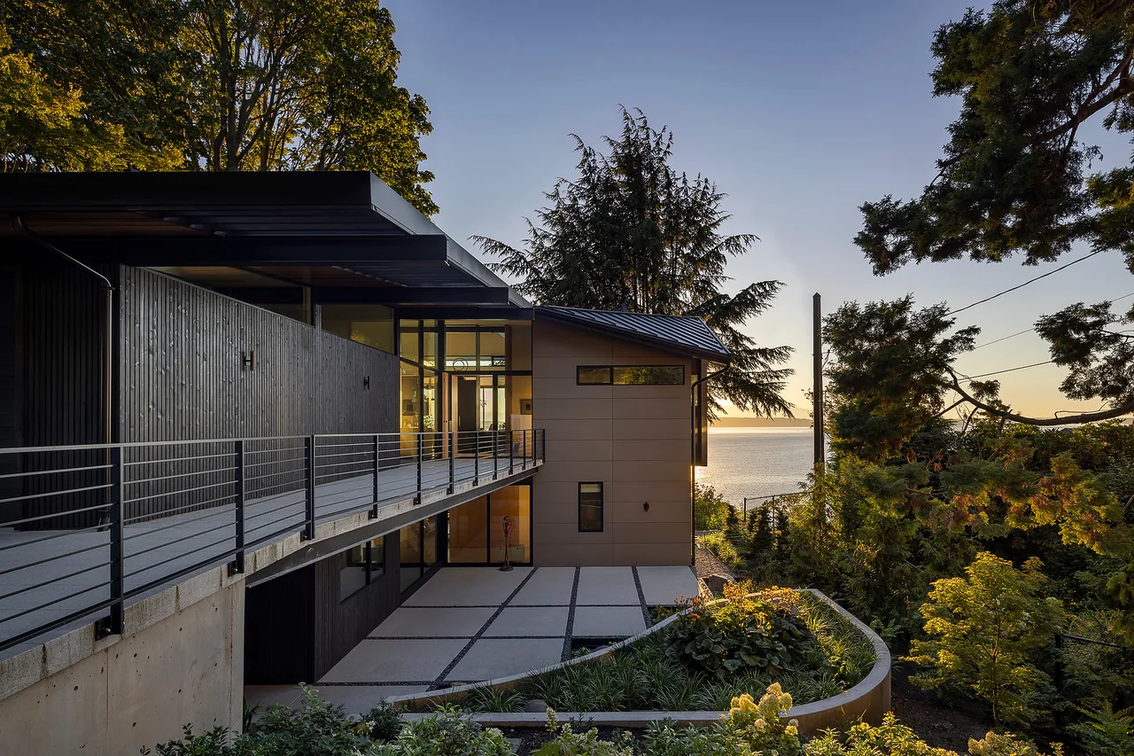 Modern home featuring a cantilevered metal walkway and mixed siding materials beside a water view in Seattle.