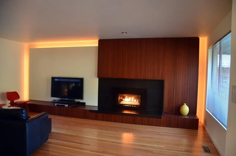 Modern living room featuring a wood-paneled fireplace wall with integrated TV and ambient backlighting.