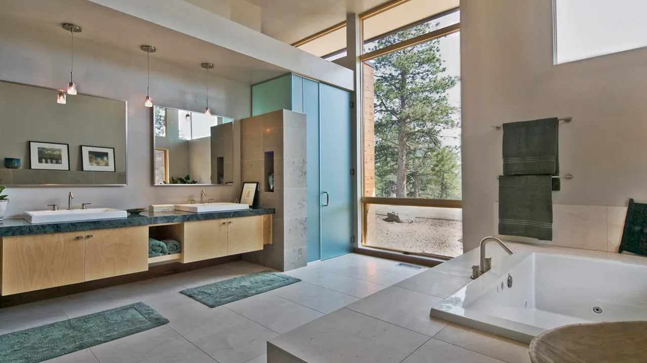 Evergreen Modern bathroom features a floating double vanity and a soaking tub next to a large window with forest views.