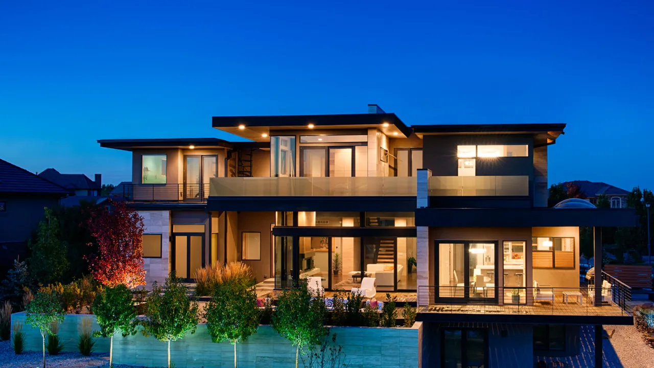 Modern two-story house featuring floor-to-ceiling glazing and black window frames with a balcony on the upper floor.