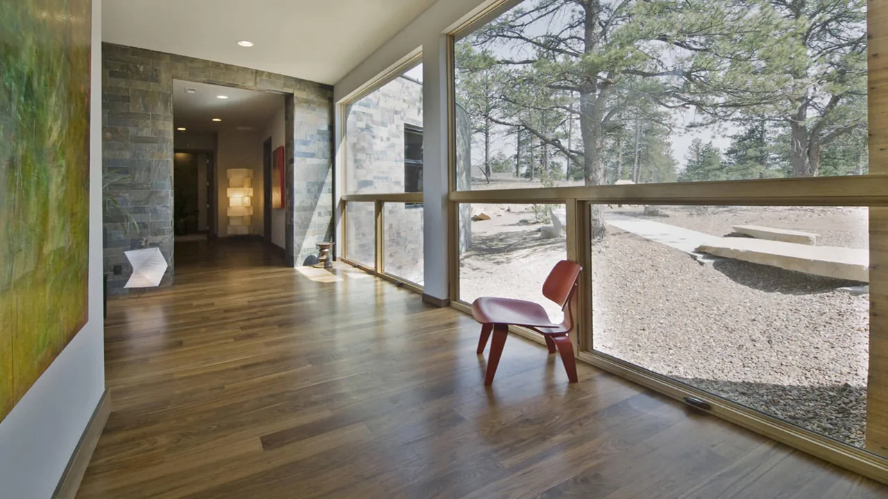 Hallway space with expansive floor-to-ceiling windows featuring wood flooring and stone wall accents.