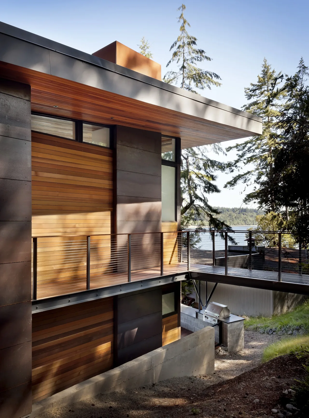 Herron Island Cabin features horizontal wood siding with metal panel accents and an overhanging roof near lakefront.