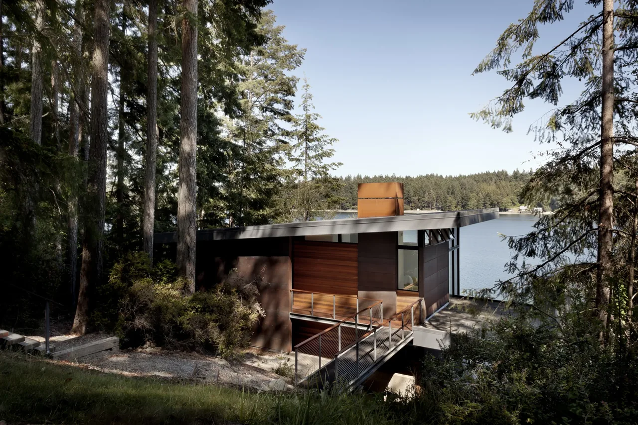 Herron Island Cabin by First Lamp Architecture Construction features a flat roof and wood siding with lake views.