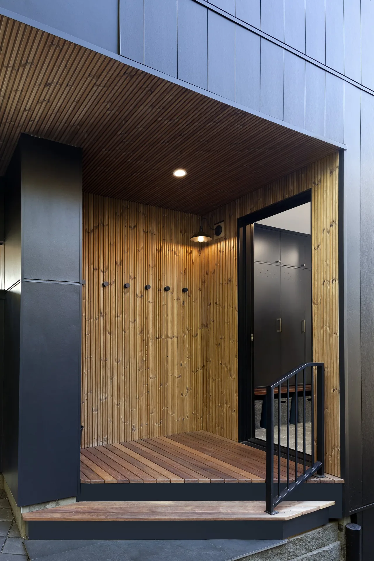 Exterior entry porch of Ravenna House featuring vertical wood siding and black metal accents.