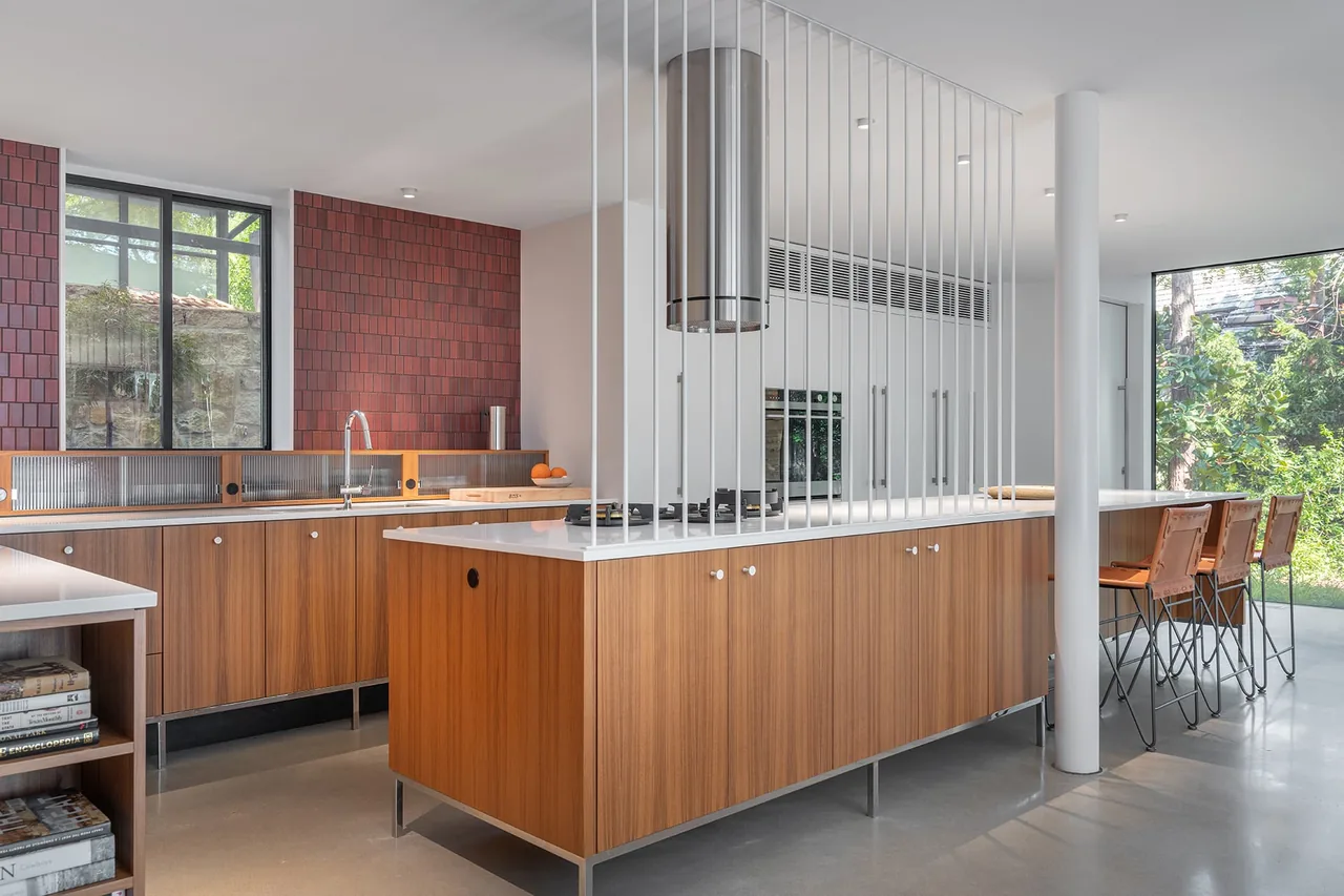 Kivett Redux kitchen features wood cabinetry with a red tile backsplash and large windows.