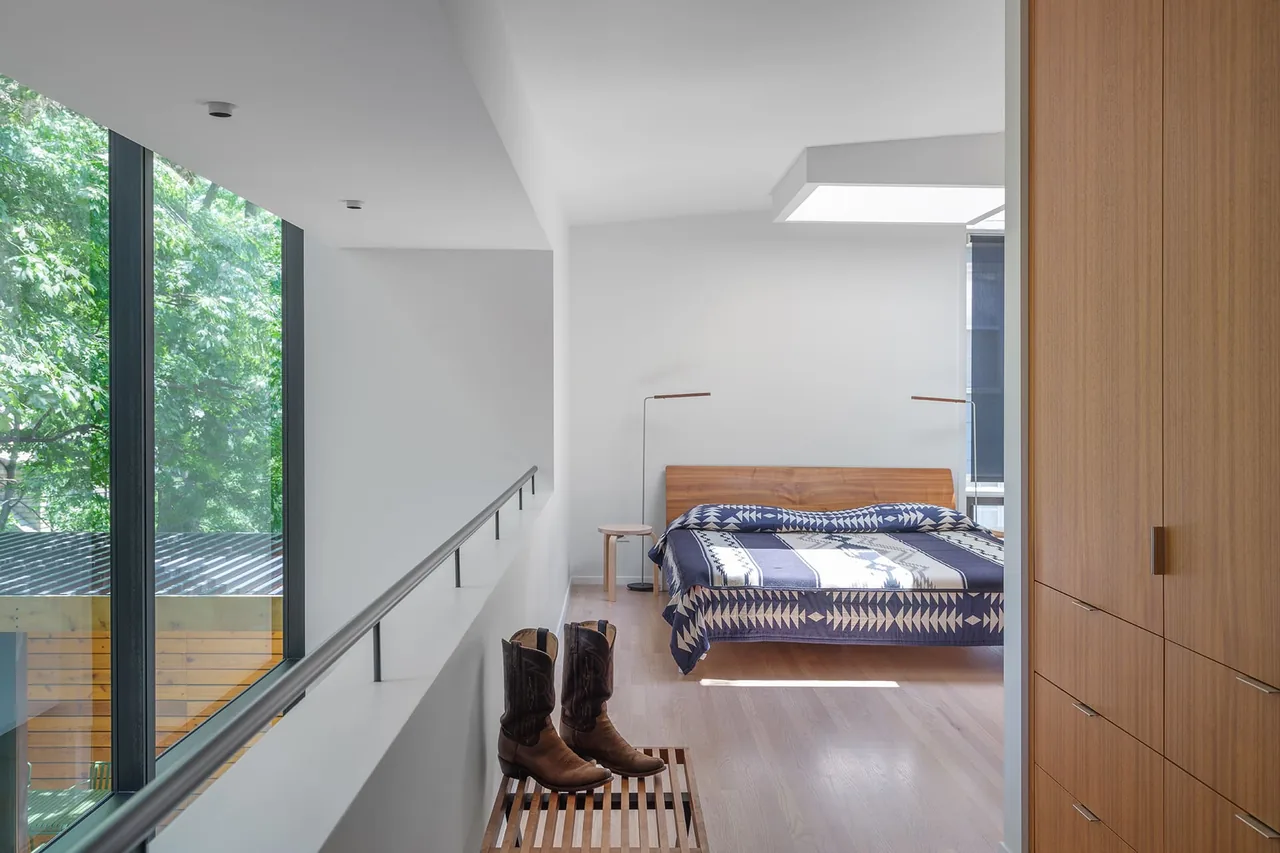 Bright bedroom with wood-paneled cabinets and a wooden bed with patterned bedding under natural light.