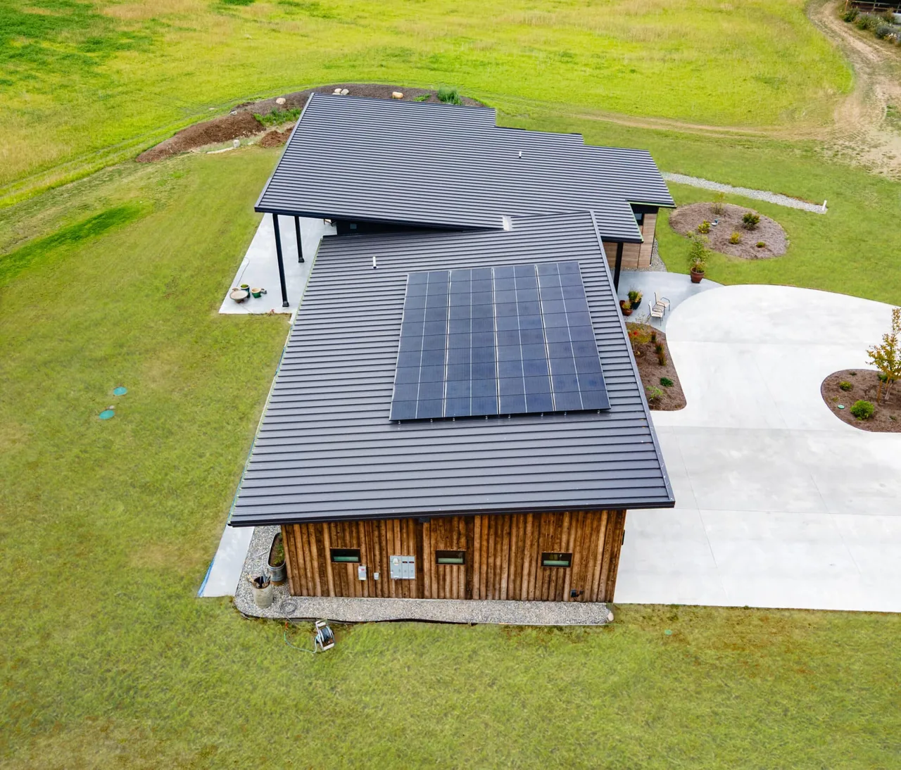 Rammed Earth House featuring a standing seam metal roof with solar panels and vertical wood siding.