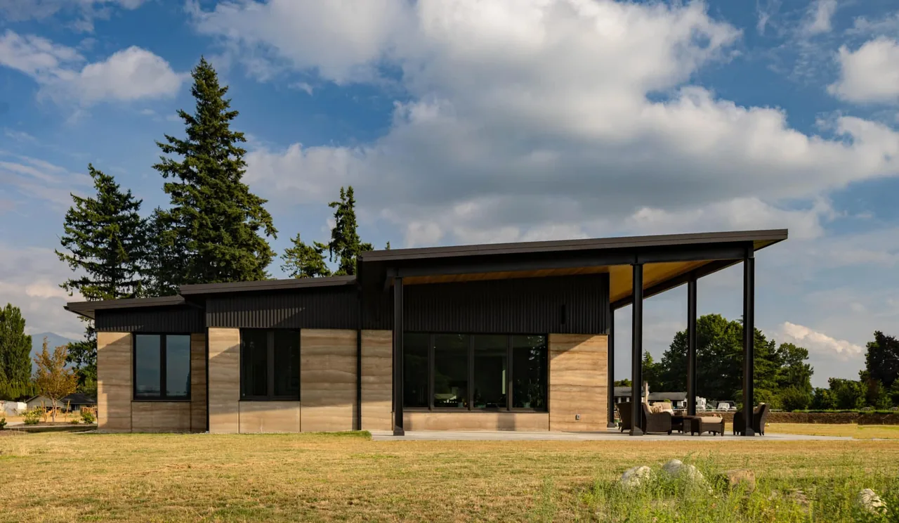 Rammed Earth House features rammed earth walls and a sleek sloped roof in a modern design by Designs Northwest Architects.