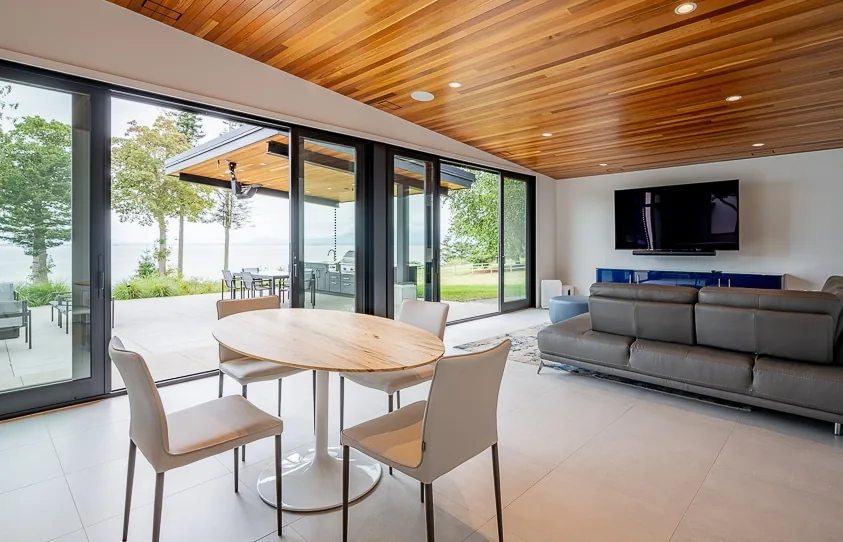 Living and dining area with floor-to-ceiling glazing opening to an outdoor patio at Cliff House ADU.