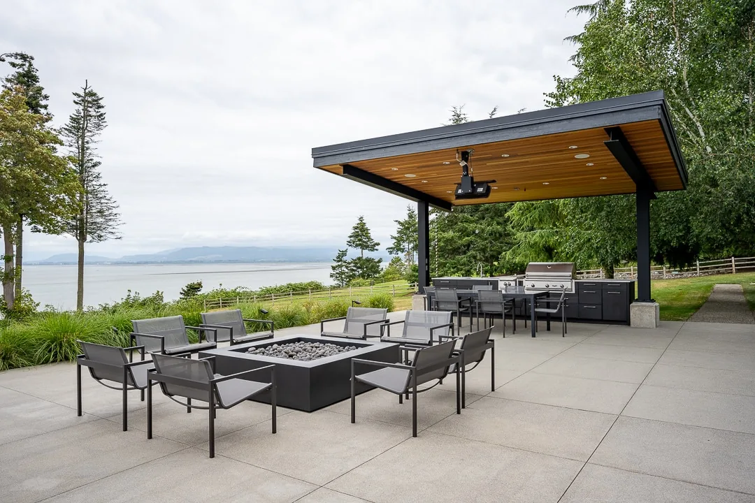 Outdoor patio of Cliff House ADU includes fire pit seating and a covered grilling station with natural wood ceiling.