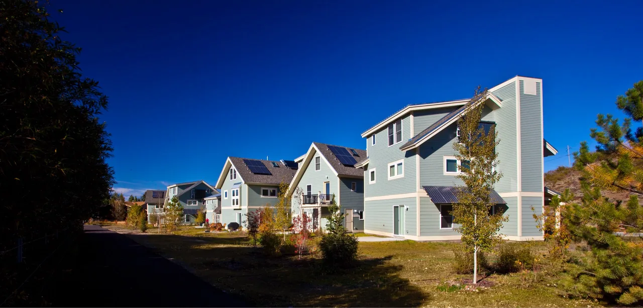Snow Creek Cottages feature modern three-story designs with solar panels and light blue siding.