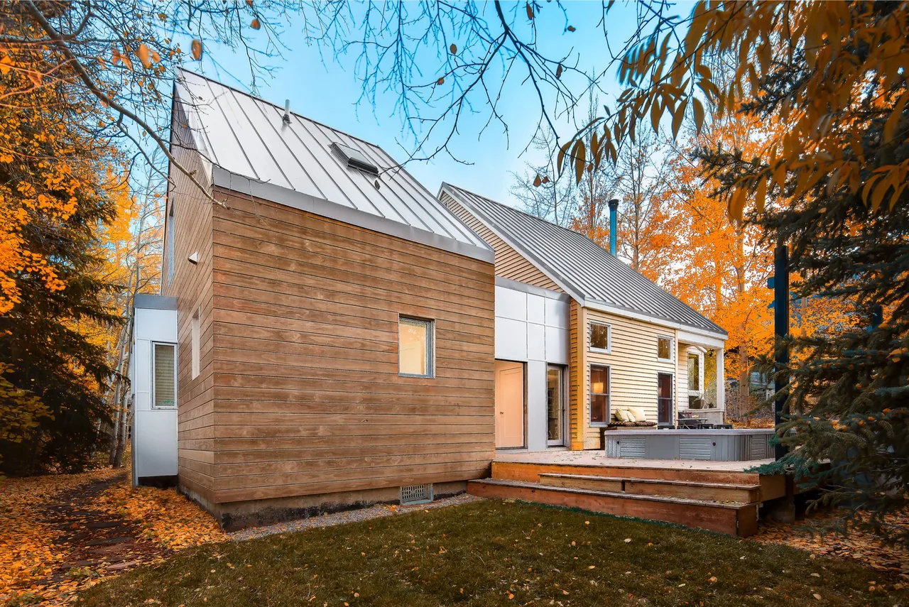 The Granny Pod project features a small modern home with wood siding and standing seam metal roofs, pictured here from the rear in fall.