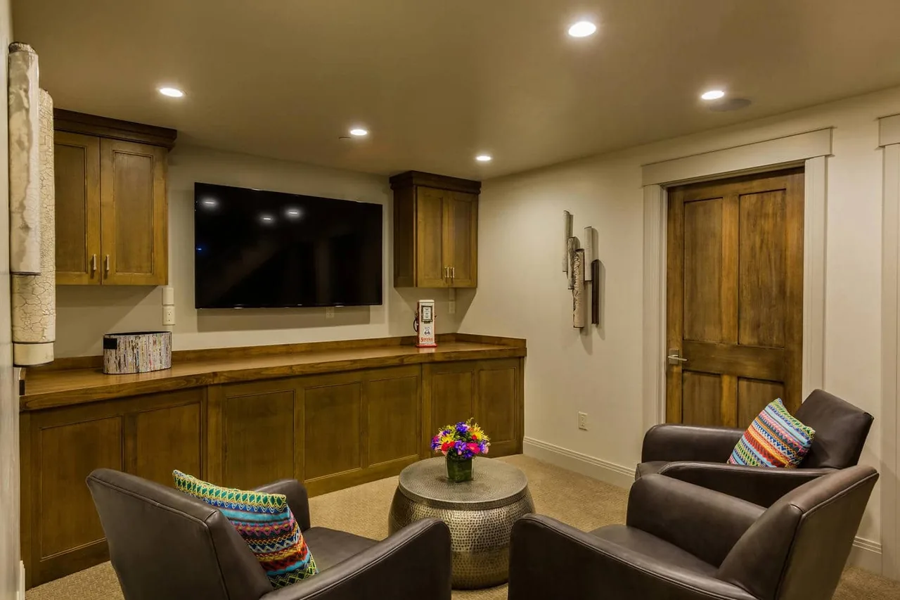 Media room featuring wood cabinetry with glass doors and dark leather armchairs.