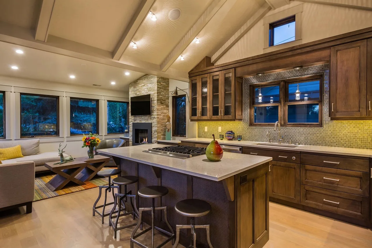 The Norfolk Ave 1 features a vaulted ceiling kitchen and living room with a stone fireplace and wooden cabinetry.