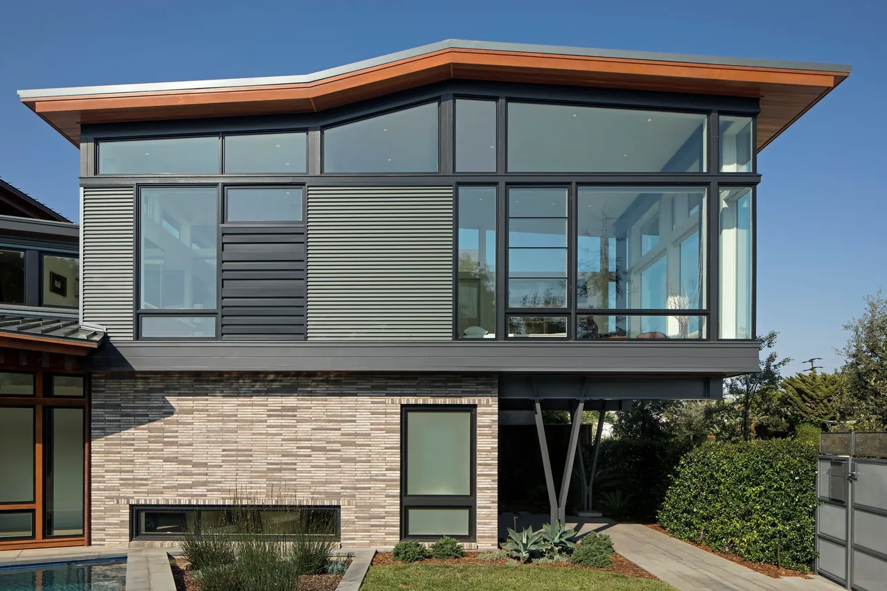 The Venice project by FINNE Architects features large black-framed windows with horizontal metal siding above a brick first floor and a wide overhanging roof.