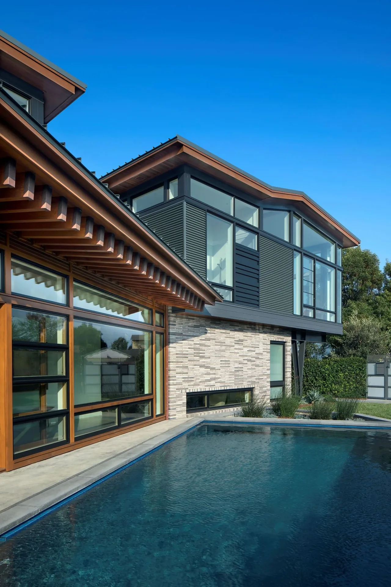 Exterior rear view of Venice home by FINNE Architects featuring wide overhangs and large horizontal windows above a pool.
