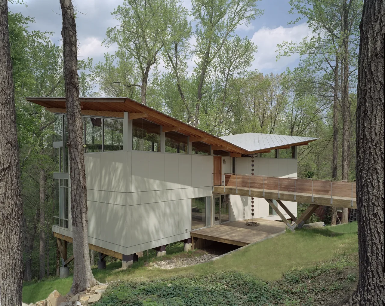 Strickland-Ferris Residence features a cantilevered exterior with a sloped roof and elevated walkway in a wooded setting.