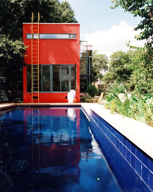 The Harmon Residence features a bold red exterior rear facade with floor-to-ceiling windows and a swimming pool with blue tile.