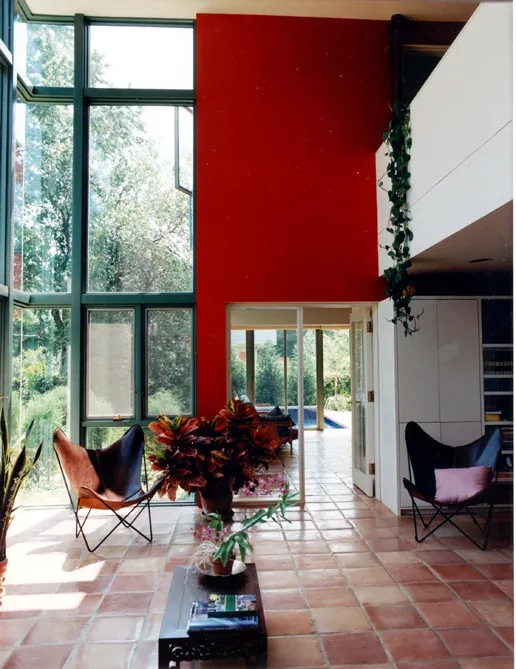 Living room at Harmon Residence features terracotta tiles, floor-to-ceiling glazing, and butterfly chairs.