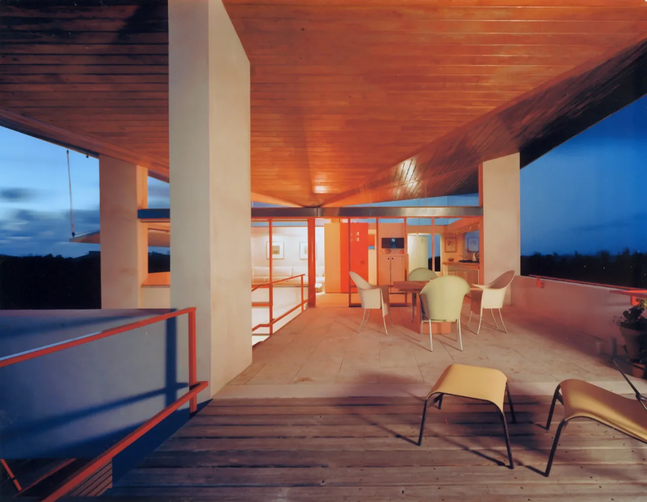 The Taylor Vacation Home features an open upper deck with a wood ceiling and red metal railing, overlooking a twilight sky.